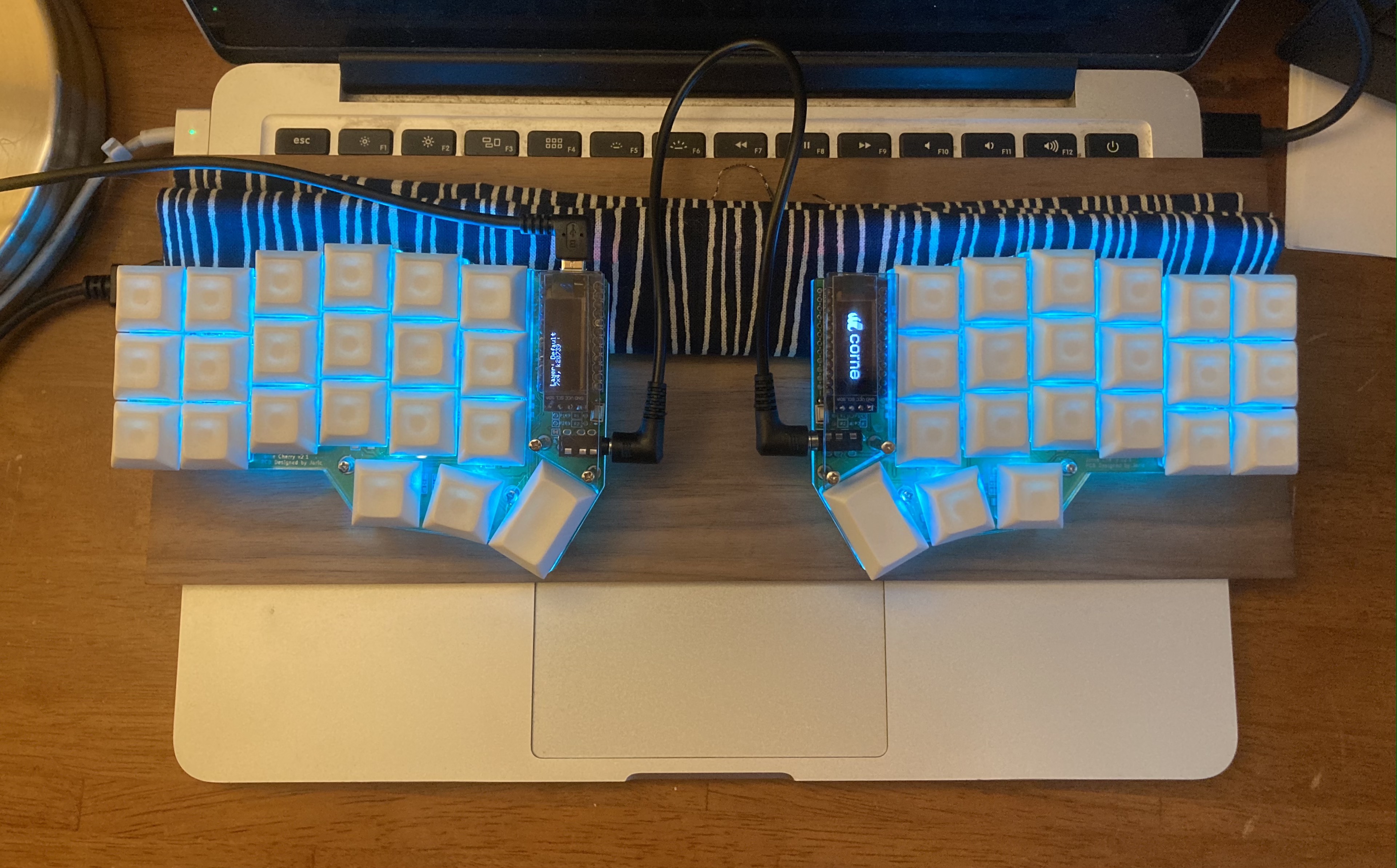 crkbd sitting on top of a rolled up cloth and board on top of a laptop keyboard.